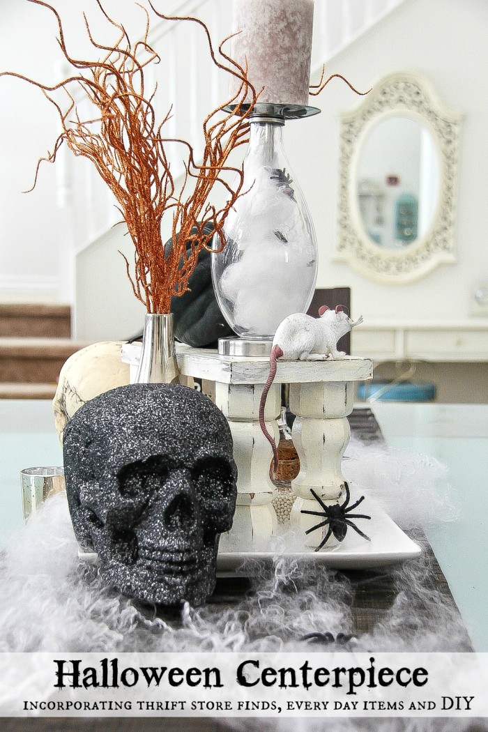 a Halloween centerpiece for a dining table with black glitter skull, candles, spider webs and more