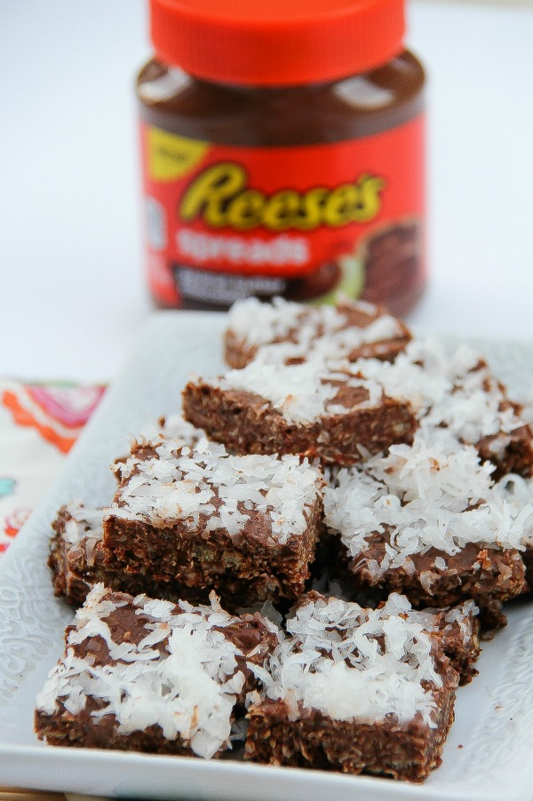a jar of Reese's spread behind chocolate peanut butter and coconut squares