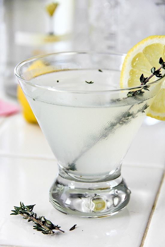 lemon drop cocktail in a glass and garnished with thyme and a lemon slice