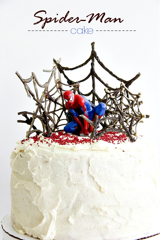 a decorate spider-man cake with webs and a toy spider-man sitting on top