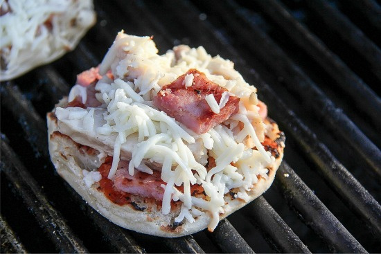 English muffins cooked on a grill with pizza toppings
