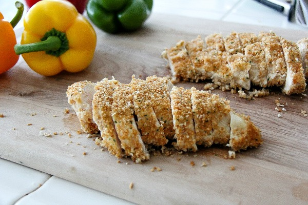 baked crumbed chicken breasts sliced into pieces on a cutting board