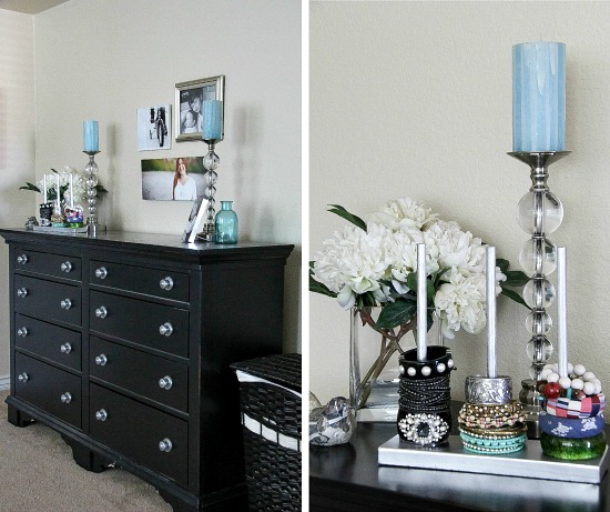 a black chest drawers topped with candle sticks, photo frames and jewelry