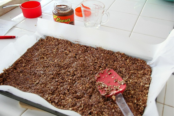 oats and chocolate being spread on a baking tray lined with parchment paper