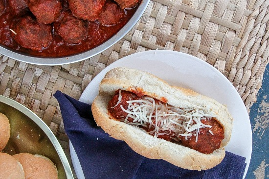 a meatball sub on a white plate with blue napkin