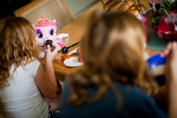 a girl feeding a plush pink kitty a muffin