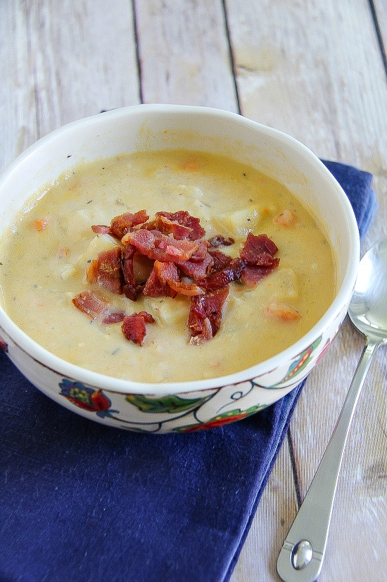 creamy potato soup in a white bowl topped with bacon pieces