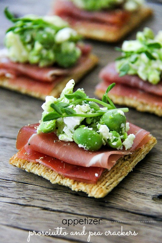 prosciutto on crackers topped with peas, feta cheese, and microgreens