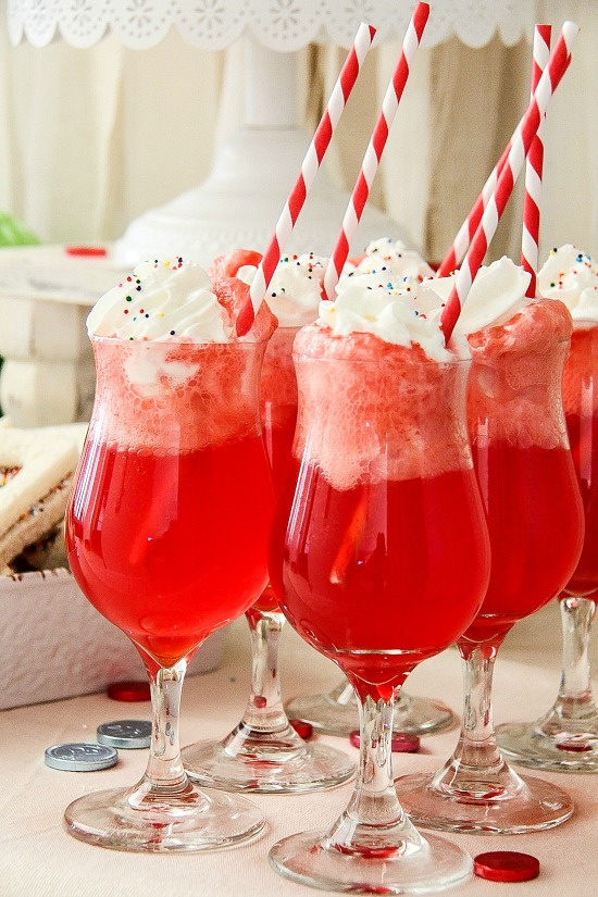 a red ice-cream float topped with ice-cream, whipped cream, and rainbow sprinkles