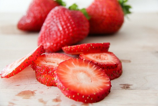 fresh strawberries sliced in a cutting board