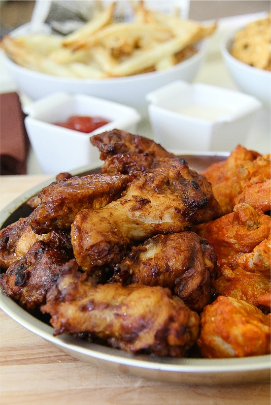 buffalo and BBQ wings on a silver dish with fries and condiments