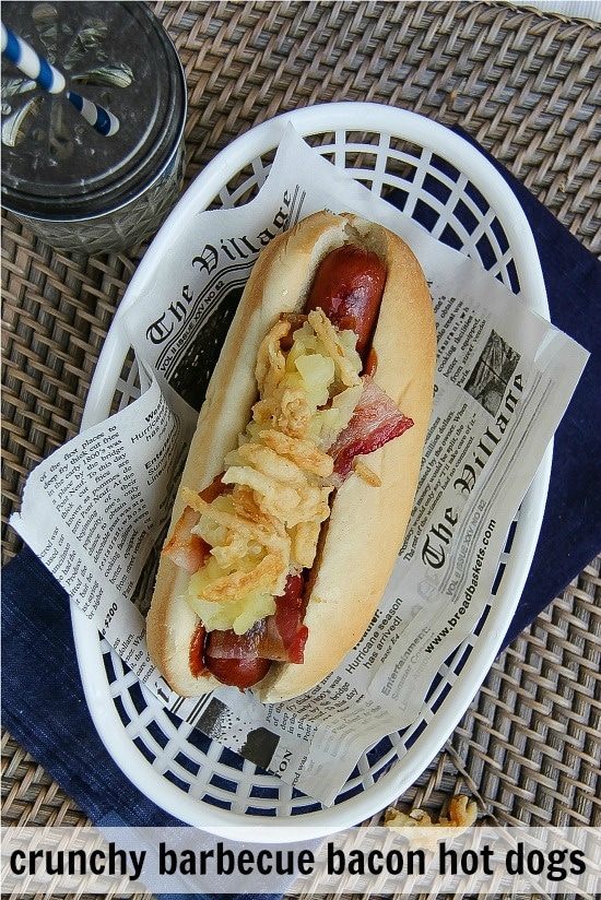 hot dogs on newspaper print paper topped with french fried onions and bacon