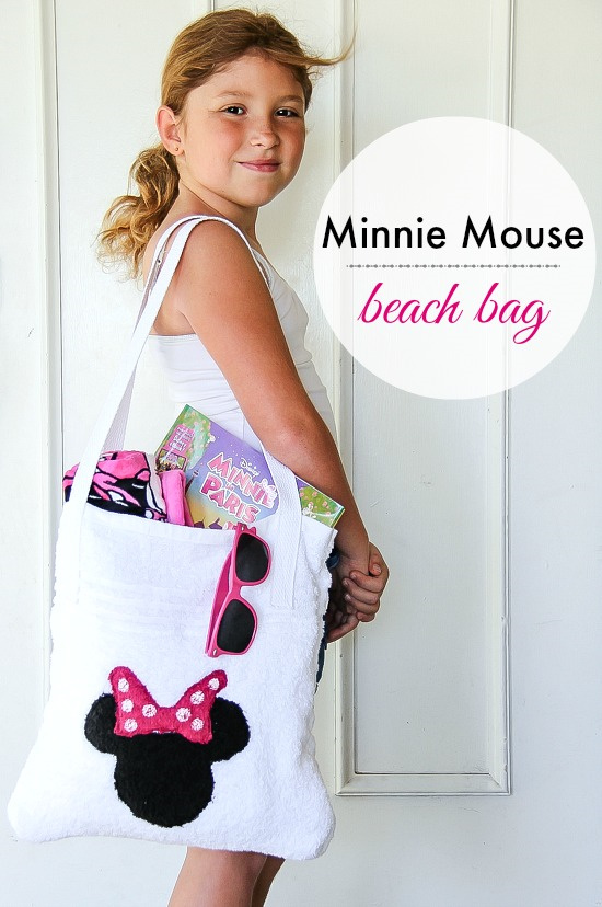 a girl holding a Minnie Mouse beach bag filled with beach stuff.