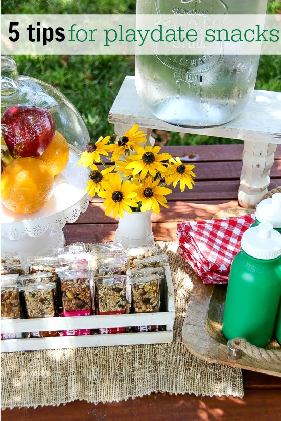 a snack table for kids with fresh fruit, water, and taste of nature bars