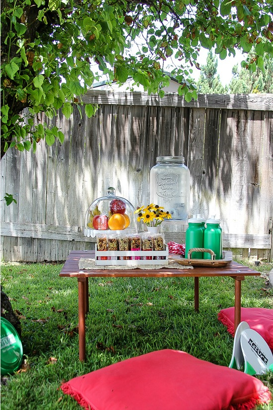 a small table set up in a backyard for kids that has healthy snacks and water