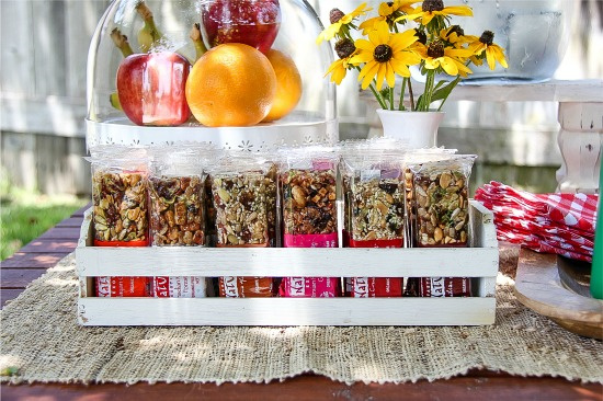 granola bars in a white wood snack holder with fresh fruit and flowers