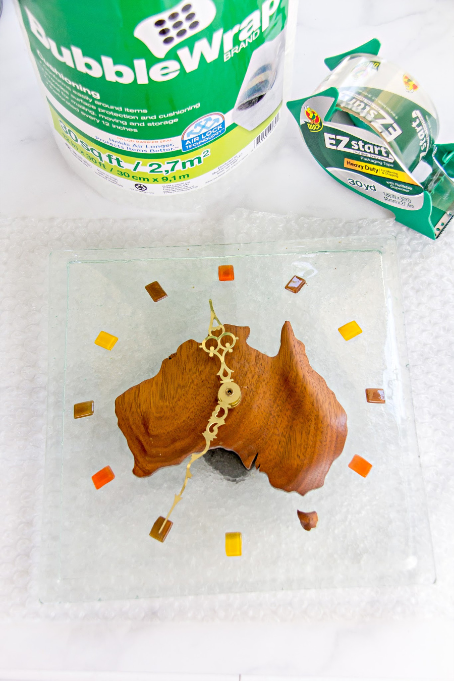 a glass and wood clock being wrapped in bubble wrap for moving