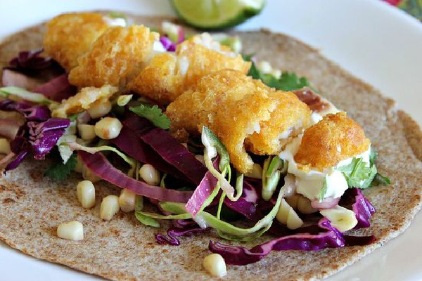 beer batter fish tacos on cabbage and corn with lime and cilantro