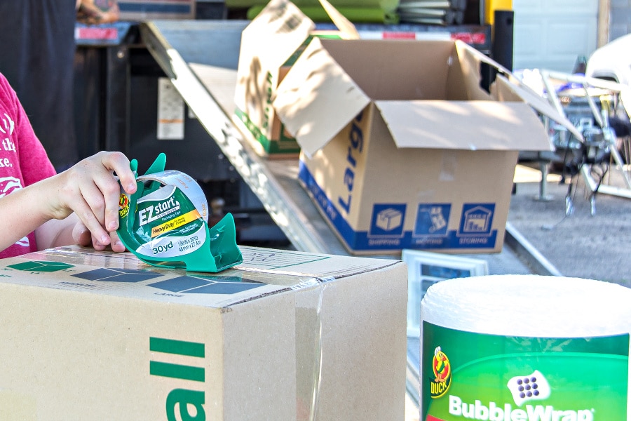 packing boxes, duck brand tape and bubble wrap and a moving truck being loaded