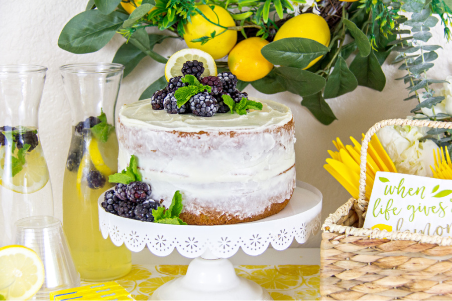 naked cake topped with blackberries with a lemon cocktail and lemon table decor