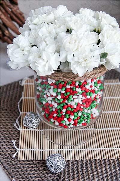 a vase filled with candy and flowers for a christmas centerpiece