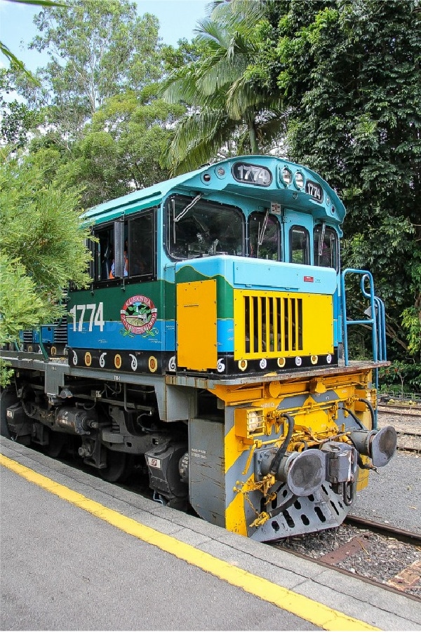 a blue, yellow, and green train that goes to Kuranda Village