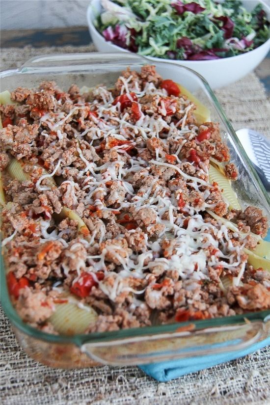 a glass baking tray filled with jumbo shell pasta, ground turkey, and ricotta cheese