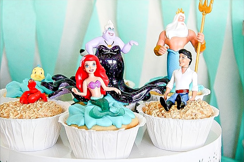 Little Mermaid cupcakes with toys on top of them.