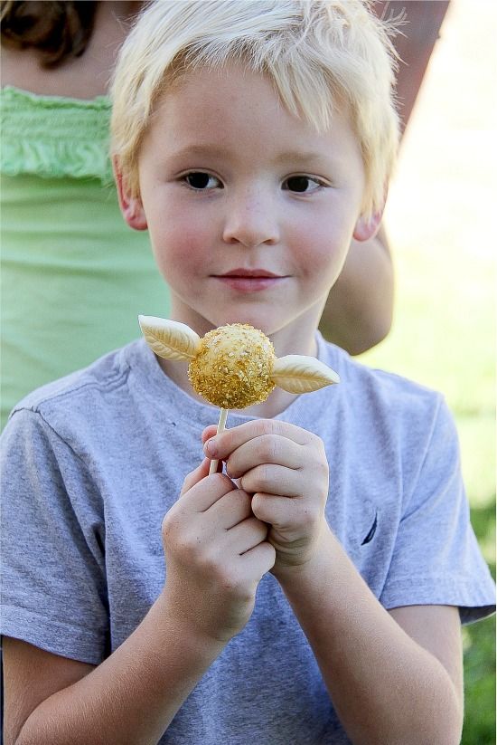 boy holding a golden snitch cake pop at a harry potter party