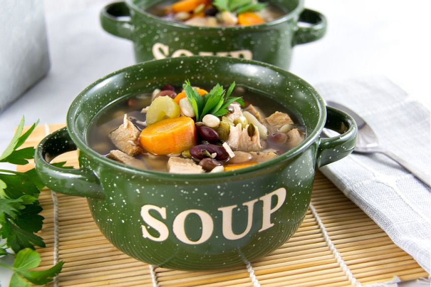 a 15 bean soup with turkey and carrots in a green soup bowl