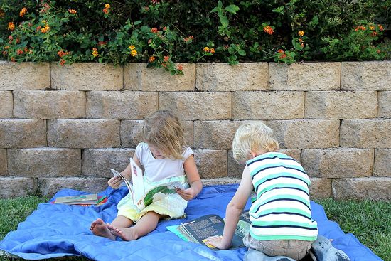 kids reading books about butterflies and caterpillars on a picnic blanket