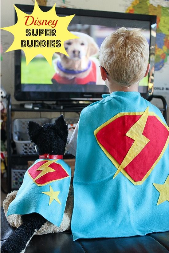 A boy and toy dog wearing super hero capes while watching Disney Super Buddies