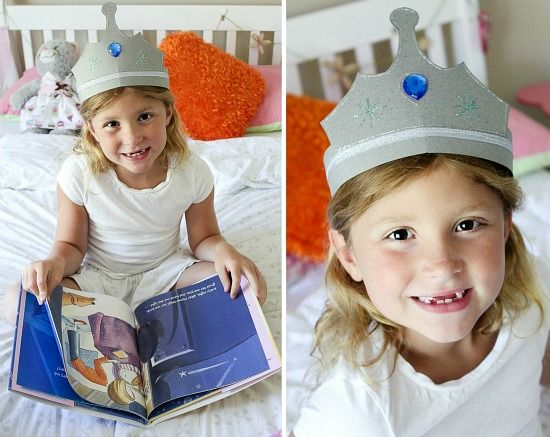 A little girl wearing a paper crown and reading Zoe's Room No Sisters Alloweed