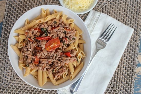 penne pasta on a white plate topped with ground turkey and fresh tomatoes