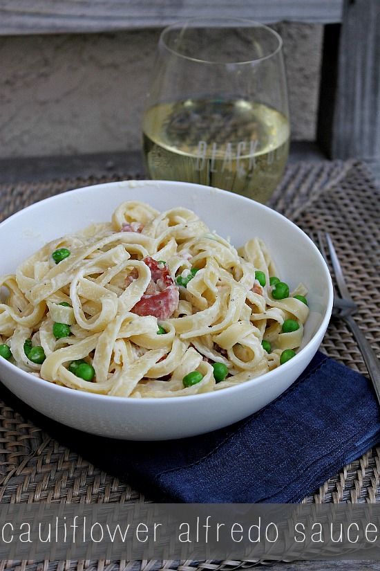 A bowl of fettucine pasta with bacon, peas, and homemade cauliflower sauce.