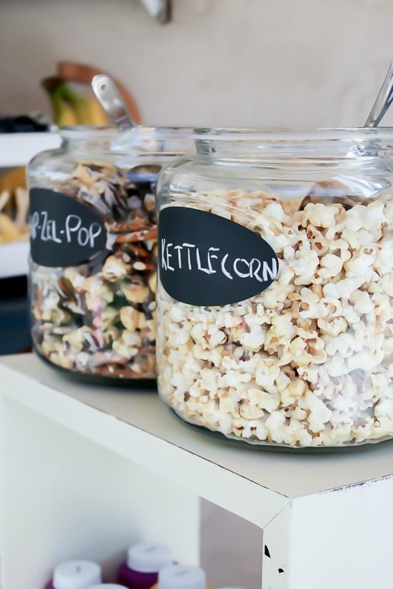 Popcorn in large glass jars with scoops for a movie night.