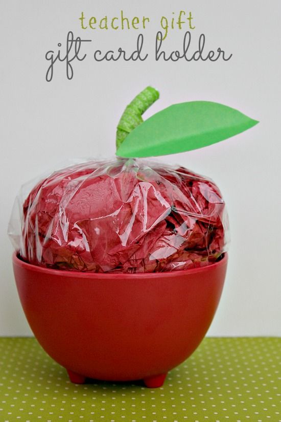 A red bowl with red tissue paper and plastic wrap hiding gifts inside that make it look like an apple.