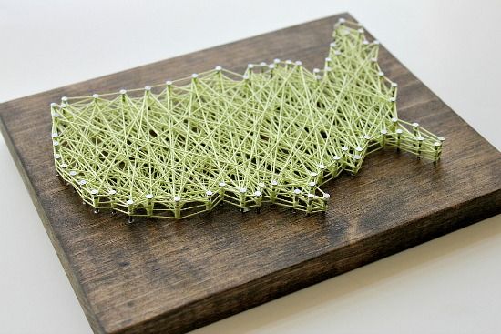 A wood block with nail and string art shaped like a map of the USA.