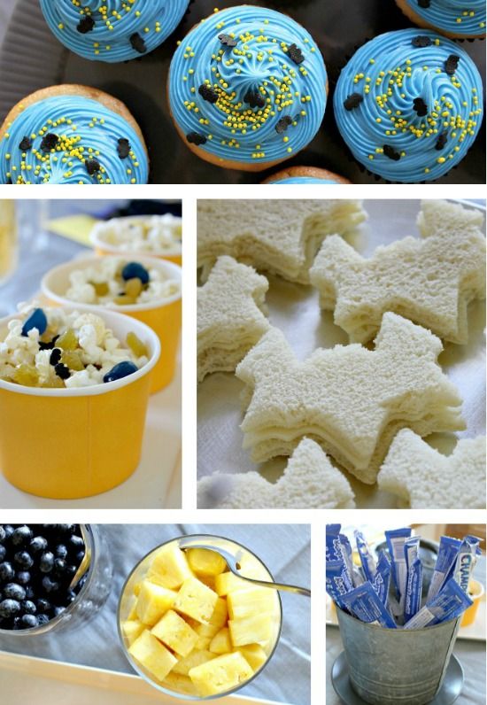 Batman themed and colored party food including popcorn mix, bat shaped sandwiches, fruit, cupcakes, and yogurt. 