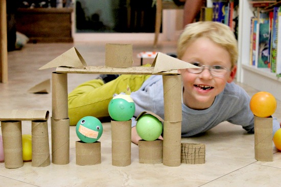 A boy playing with an Angry Birds craft and game using paper rolls.