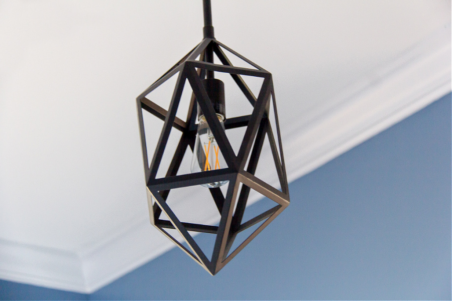 A black light hanging from the ceiling above a guest bed.