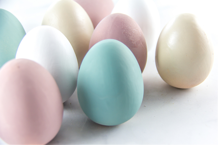 Wooden eggs painted beige, white, blue, and pink to make a door wreath.