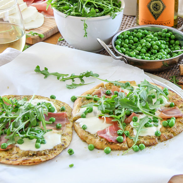 Two naan pizzas topped with peas arugula and prosciutto