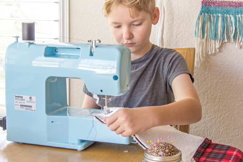 A boy learning to sew his own fleece book pillow