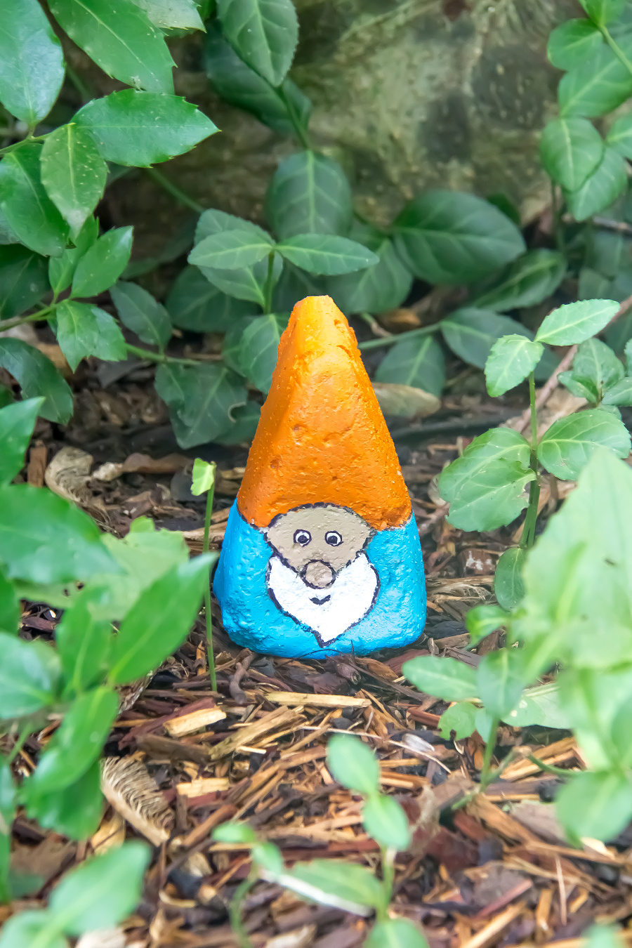A concrete diy garden gnome that is painted in a garden
