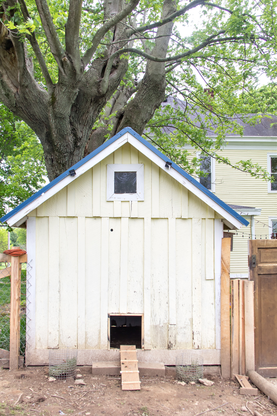 A door cut into the back of a garden shed chicken coop with a ramp.