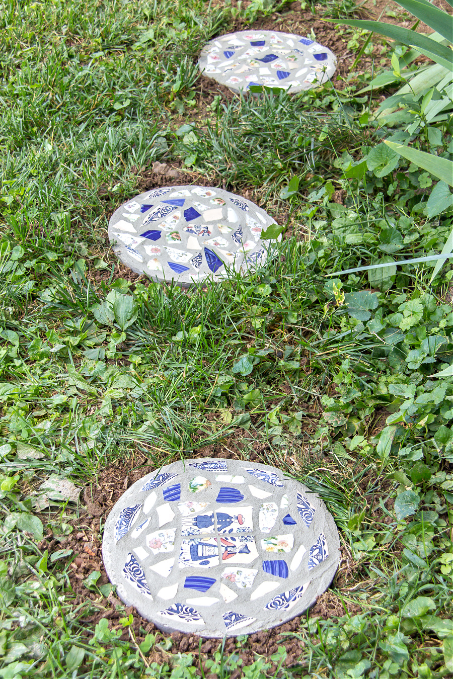 Round concrete stepping stones made with fast setting concrete and broken plates.