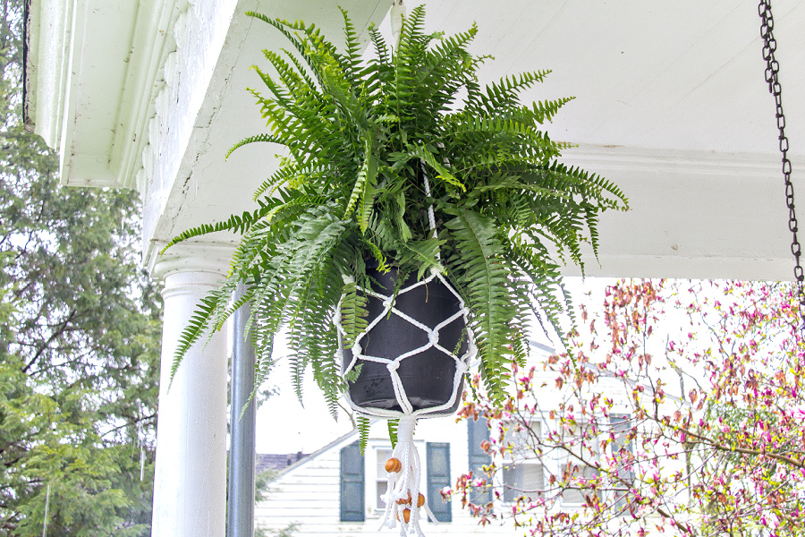 A white weatherproof macrame plant hanger for front porch ferns.