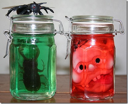 Jars with colored liquid, bugs and shrunken heads to make Halloween specimen jars for Halloween decorating.