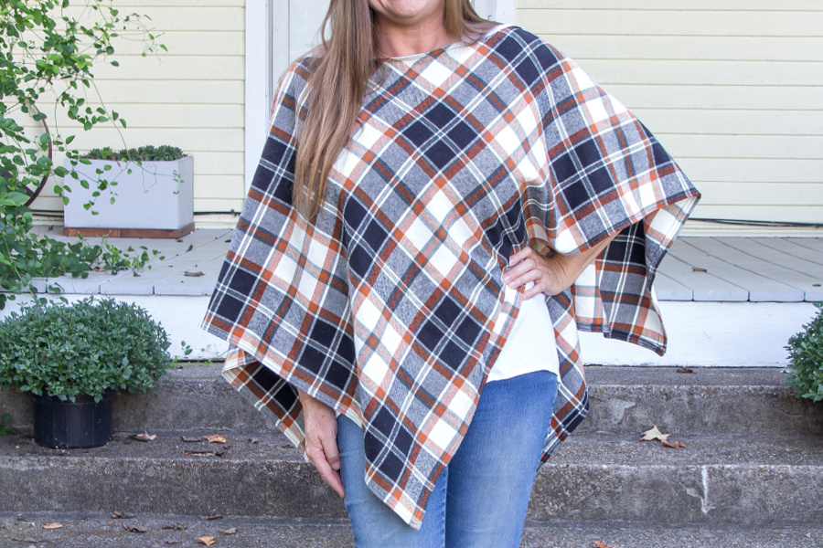 A DIY fall poncho in black, orange, and white plaid flannel pattern.